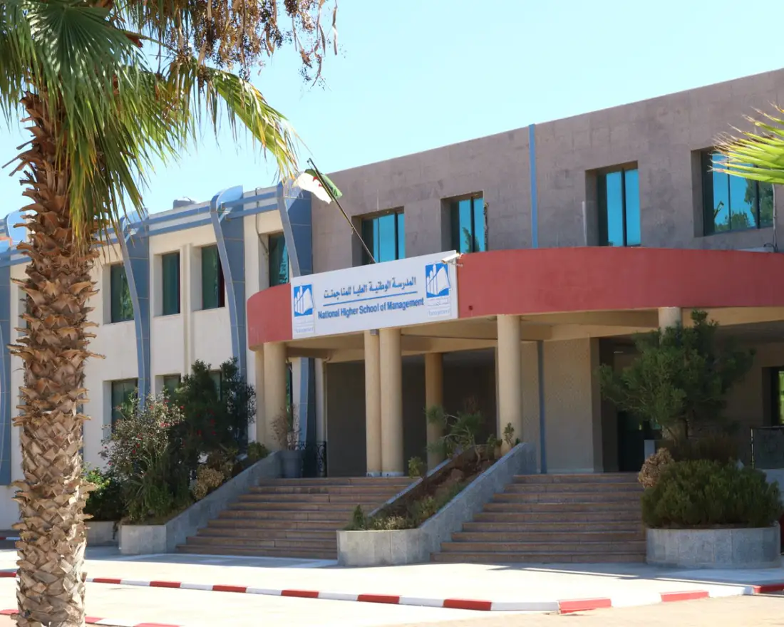The main entrance of ENSM in sunlight, behind a palm tree