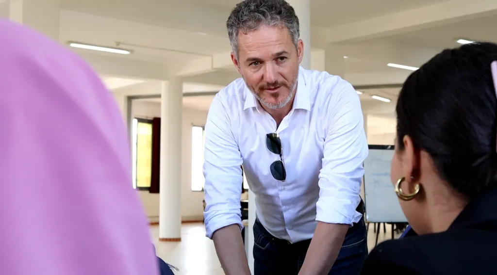 A trainer talks with two participants about their project