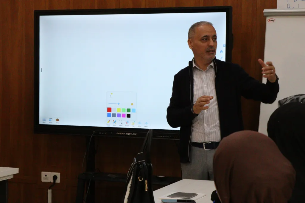 A speaker leads a workshop in front of an interactive screen